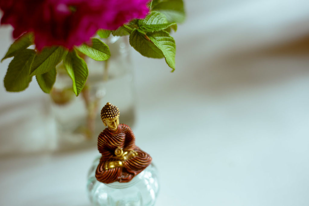 buddhist statue meditating under flowers