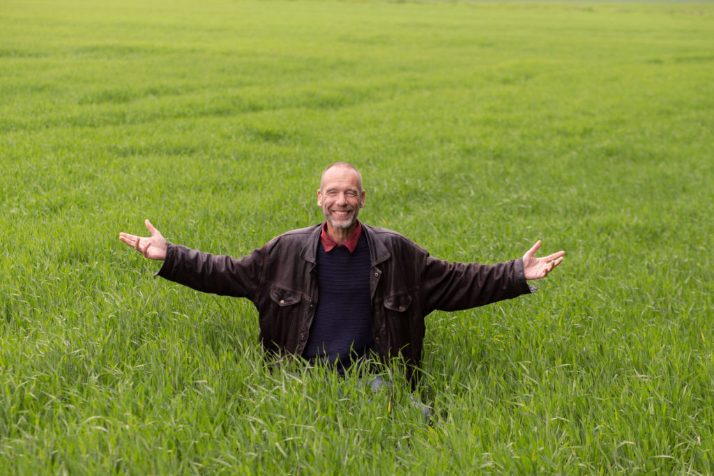 Stephan Pende in a field, opening his arm to represent guided meditations